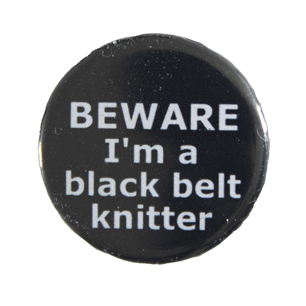 black pin badge with text "BEWARE I'm a black belt knitter"