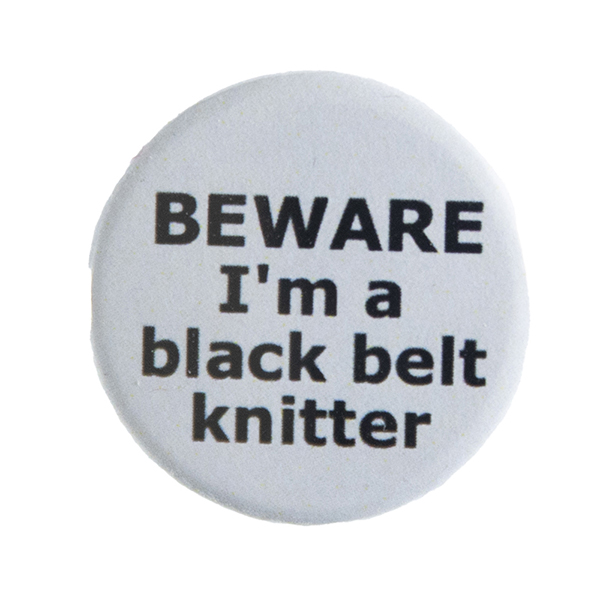 grey pin badge with text "BEWARE I'm a black belt knitter"