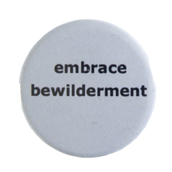 grey pin badge with text "embrace bewilderment"