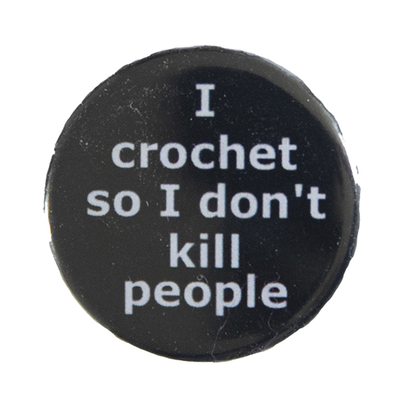 black pin badge with text "I crochet so I don't kill people"