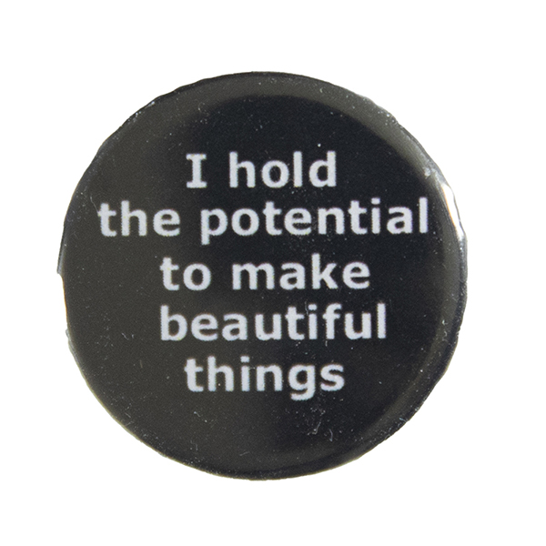 black pin badge with text "I hold the potential to make beautiful things"