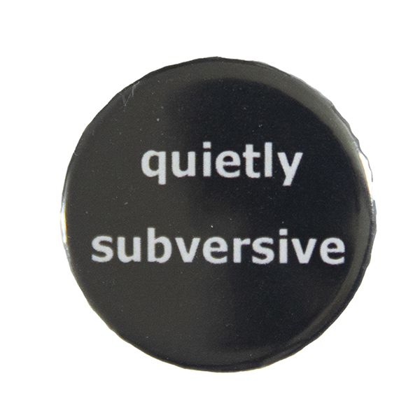 black pin badge with text "quietly subversive"
