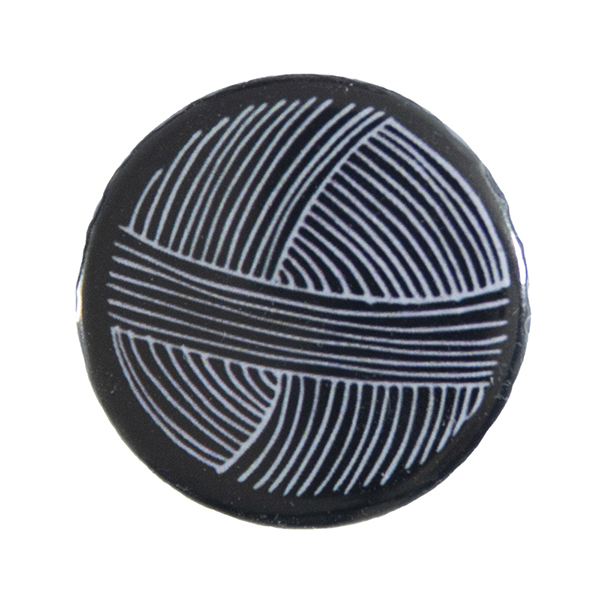 black pin badge with line drawing of a ball of yarn