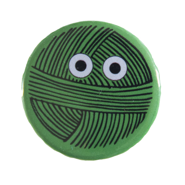 green pin badge with line drawing of a ball of yarn with eyes