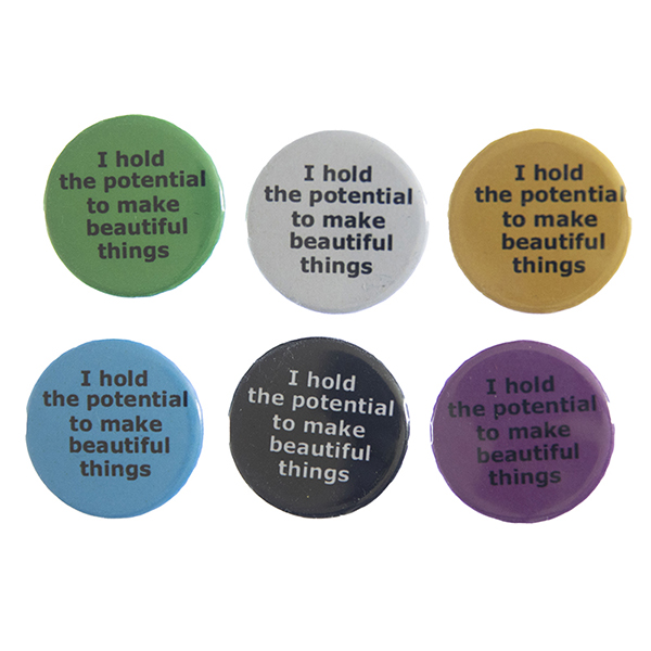 pin badges with text "I hold the potential to make beautiful things". Badges are green, light grey, yellow. blue, black and pink