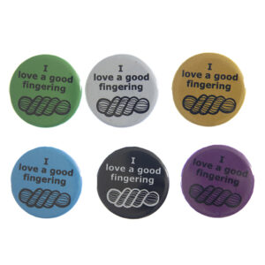 pin badges with text "I love a good fingering" and line drawing of a skein of yarn. Badges are green, light grey, yellow. blue, black and pink