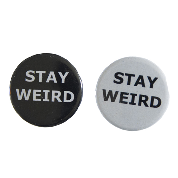 pin badges with text "STAY WEIRD". Badges are black and light grey