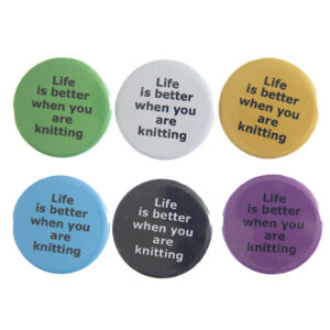 pin badges with text "Life is better when you are knitting". Badges are green, light grey, yellow. blue, black and pink