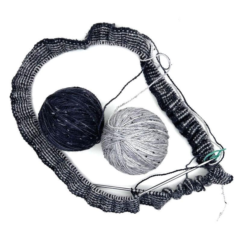 knitting on circular needles with balls of black and silver yarn