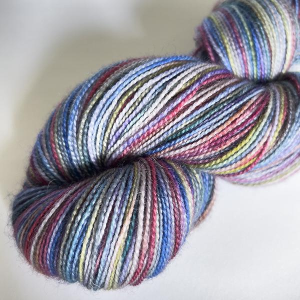 close up of skein of yarn dyed with rainbow colours and tin grey