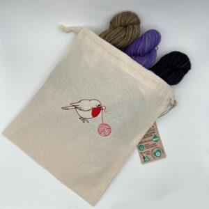 CReam cotton drawstring back embroidered with robin and ball of yarn. Bag holds 3 skeins of yarn.