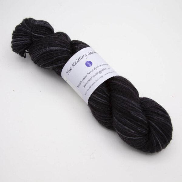 black hand dyed sock yarn, wound up in a skein with The Knitting Goddess ball band