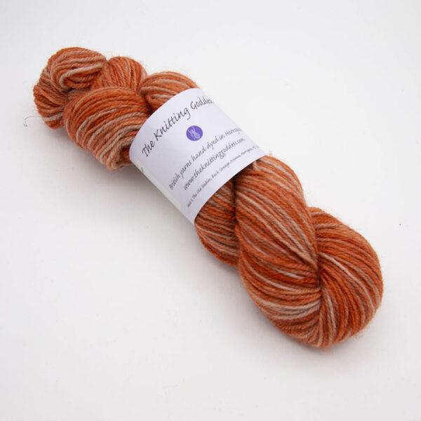 copper hand dyed sock yarn, wound up in a skein with The Knitting Goddess ball band