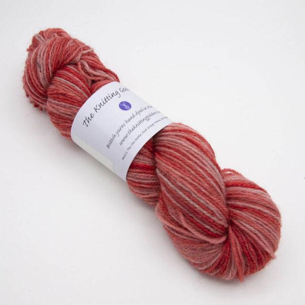 geranium hand dyed sock yarn, wound up in a skein with The Knitting Goddess ball band