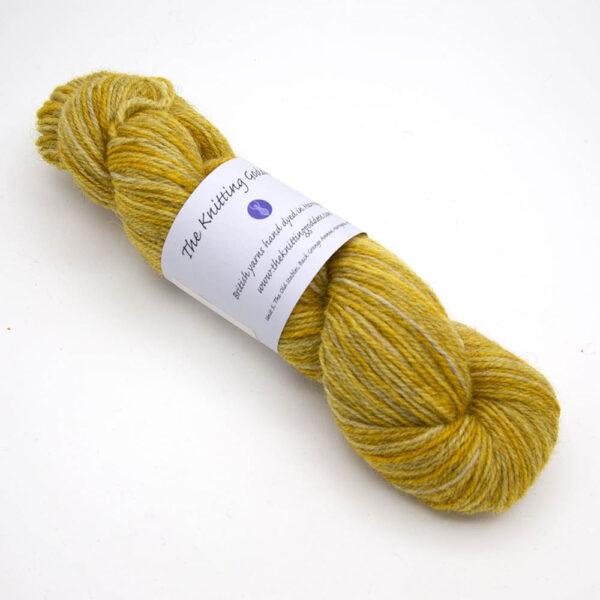 gold hand dyed sock yarn, wound up in a skein with The Knitting Goddess ball band
