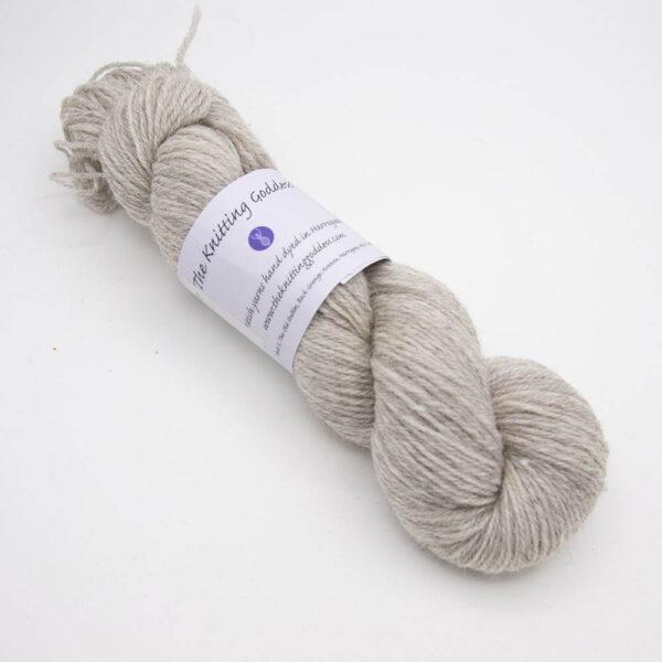 naked silver hand dyed sock yarn, wound up in a skein with The Knitting Goddess ball band