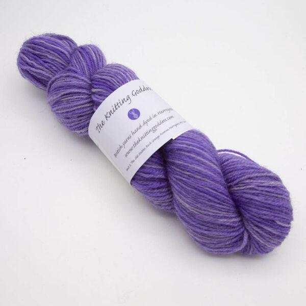 purple hand dyed sock yarn, wound up in a skein with The Knitting Goddess ball band