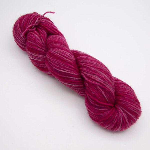 rose hand dyed sock yarn, wound up in a skein with The Knitting Goddess ball band