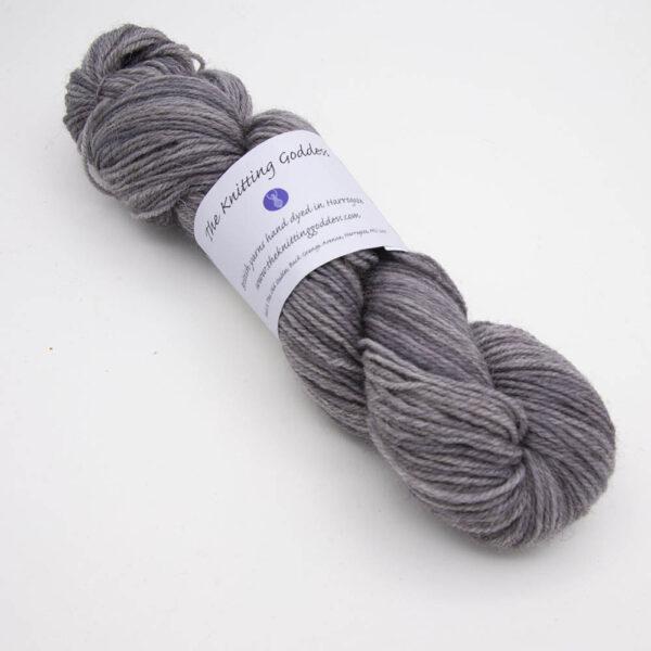 silver hand dyed sock yarn, wound up in a skein with The Knitting Goddess ball band