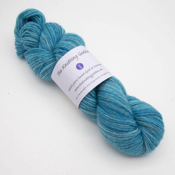 turquoise hand dyed sock yarn, wound up in a skein with The Knitting Goddess ball band