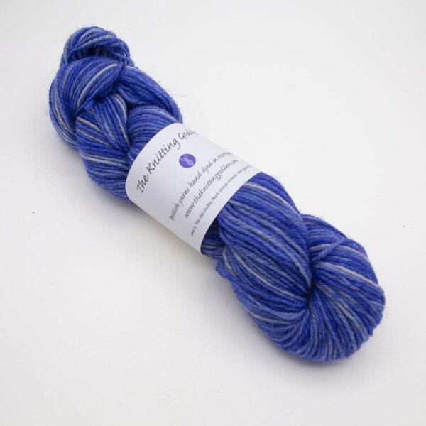 violet hand dyed sock yarn, wound up in a skein with The Knitting Goddess ball band