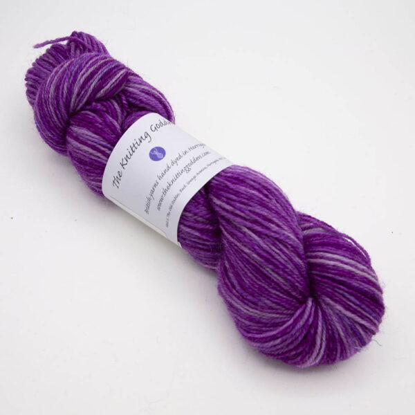 wisteria hand dyed sock yarn, wound up in a skein with The Knitting Goddess ball band