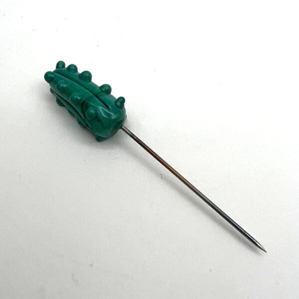 green glass pickle pin lying flt with point visible