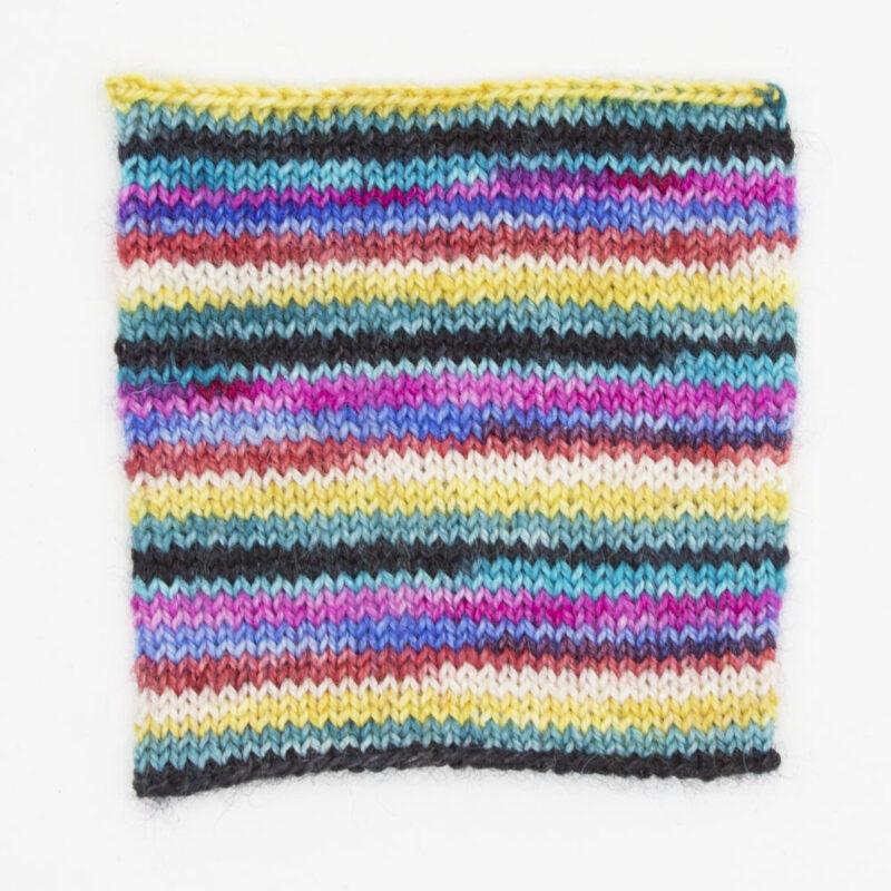 Candy is Dandy self striping sock yarn swatch, showing thin rounds of black, green, yellow, white, red, blue, pink and turquoise.