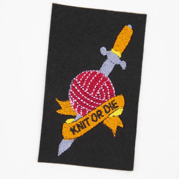embroidered patch with a dagger though a ball of yarn and banner with text knit or die