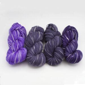 four skeins in shades of purple and grey with white flecks