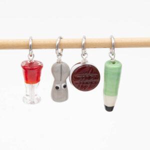 4 lampwork glass stitch markers with jump rings. Glass of red wine, bunny, biscuit and pencil.