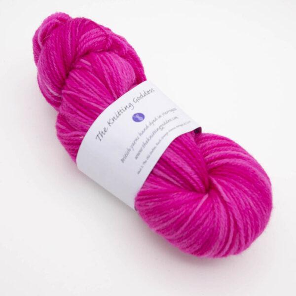 skein of magenta pink DK sock wool with The Knitting Goddess ball band