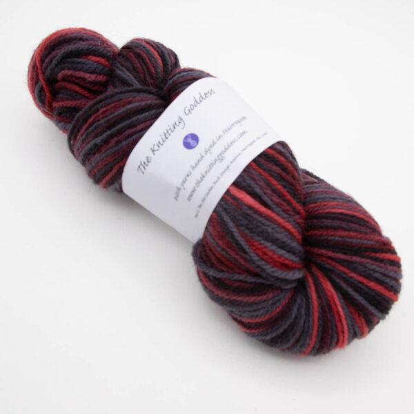 skein of menace DK sock wool dyed with red and black with The Knitting Goddess ball band