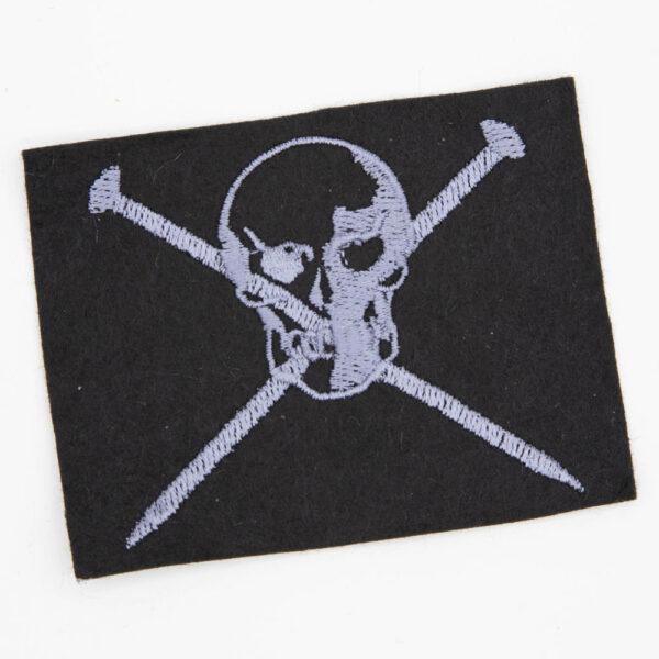 grey skull over two crossed knitting pins embroidered patch on black felt