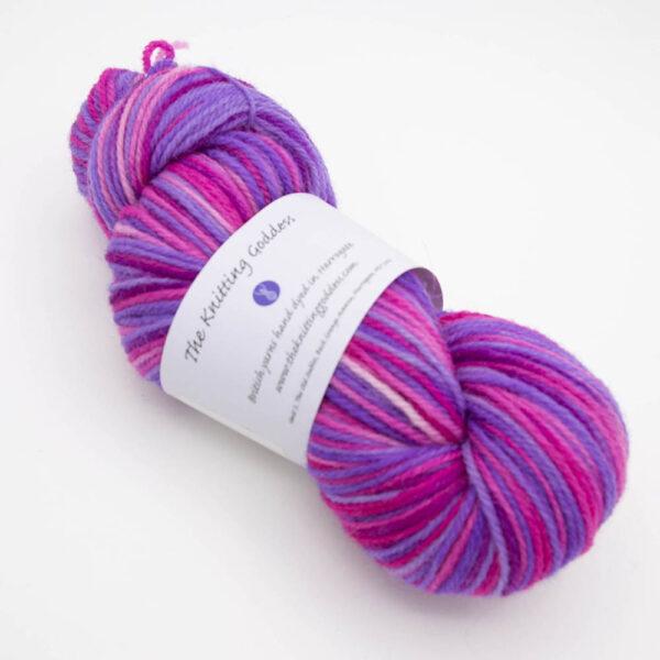 skein of sweet pea DK sock wool dyed in purple and pink with The Knitting Goddess ball band