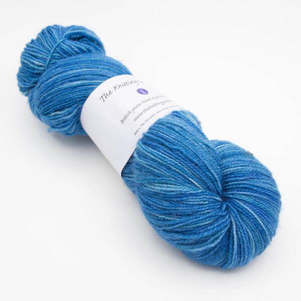 skein of teal blue Bluefaced Leicester and nylon yarn which has a high twist and The Knitting Goddess ball band