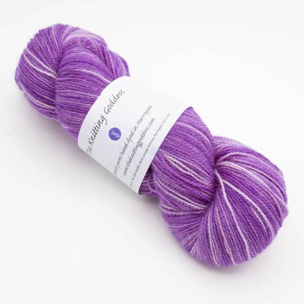 skein of wisteria (pinkish purple) Bluefaced Leicester and nylon yarn which has a high twist and The Knitting Goddess ball band
