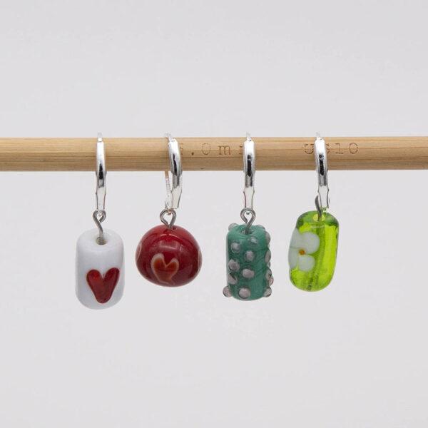 February glass stitch markers. red heart on white, white outline heart on red, cherry blossom on green and white flower on lime green