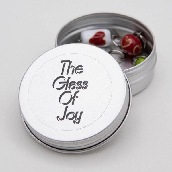 round metal tin with The Glass Of Joy label