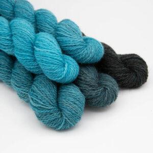 Set of five mine skeins in a turquoise gradient which starts as bright turquoise and ends as black. Mini skeins are arranged in a pyramid.
