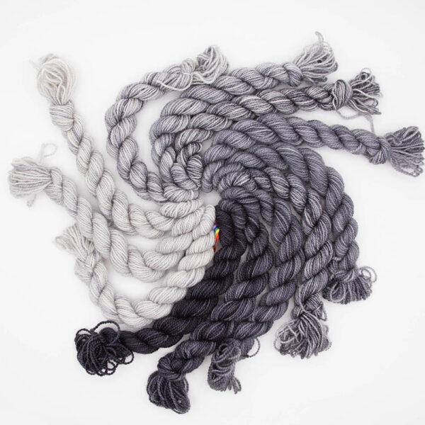 set of 12 mini skeins dyed in a grey fade arranged in a spiral