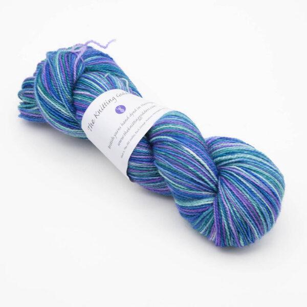 skein of hand dyed kingfisher yarn in blue, purple and green with The Knitting Goddess ball band.
