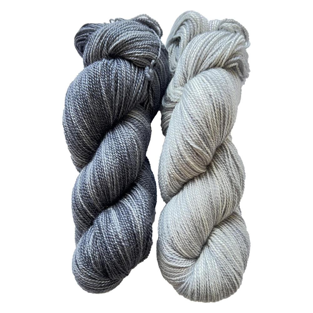 two skeins of yarn, one charcoal grey, the other pale pearl grey